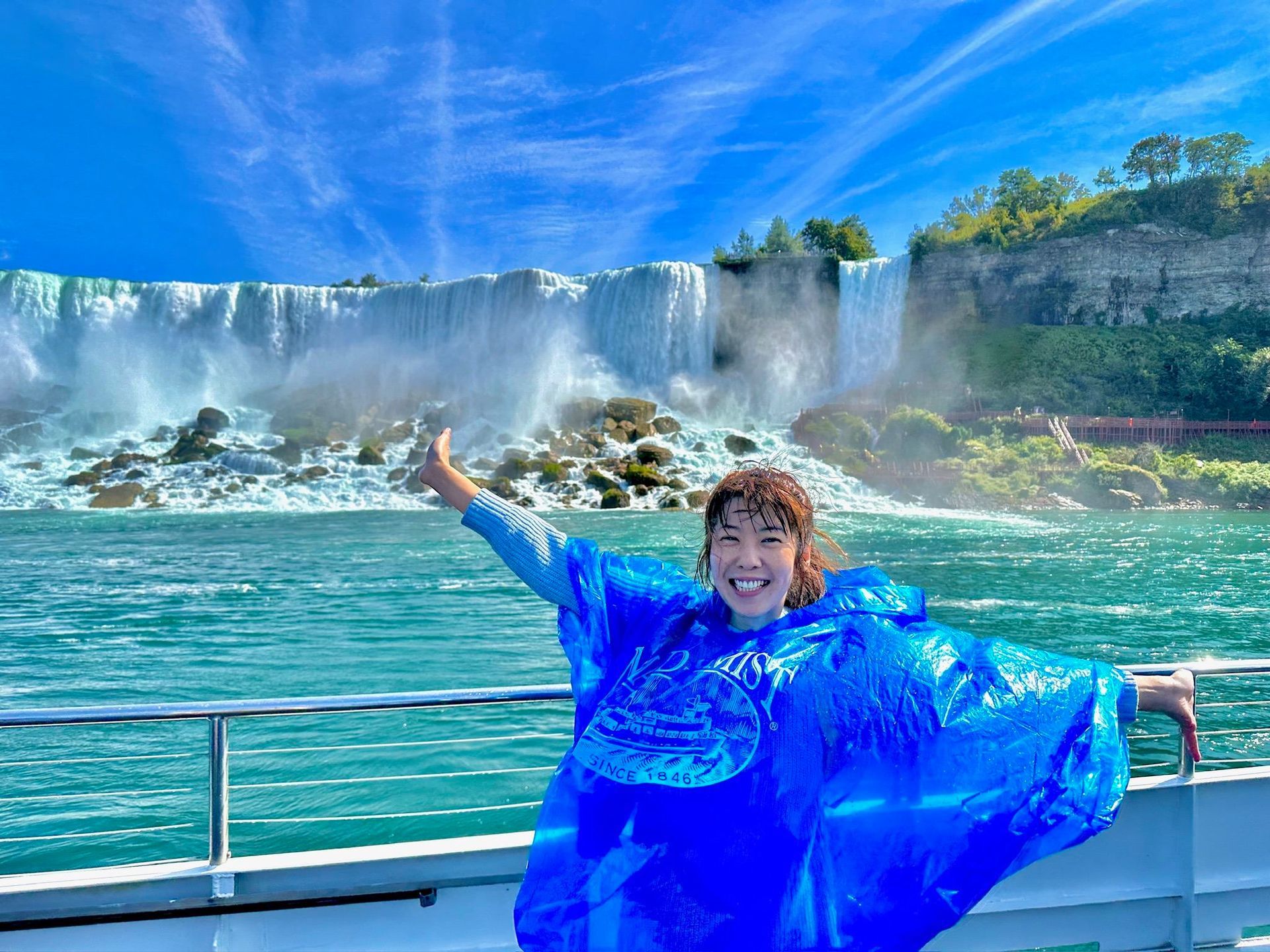 A boat with people on it is in front of a waterfall.