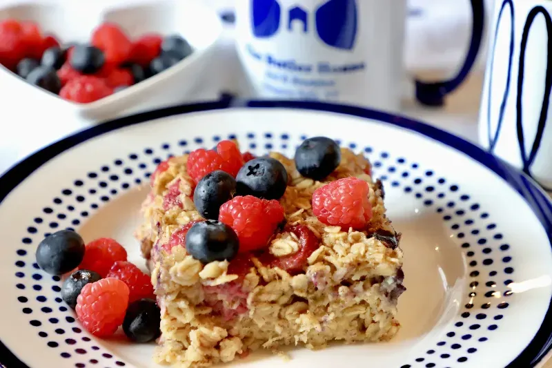 A piece of oatmeal with raspberries and blueberries on a plate.