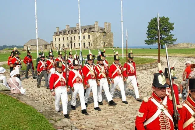 A group of men in red uniforms marching in front of a building