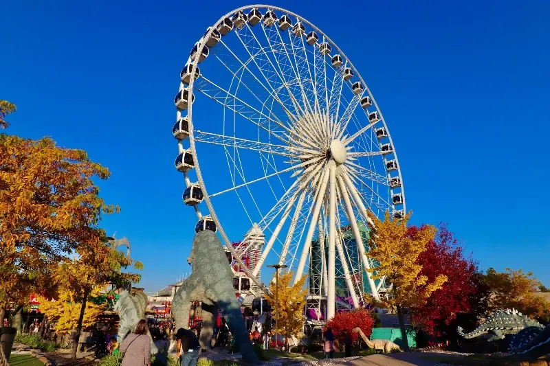 A large ferris wheel is surrounded by trees and people