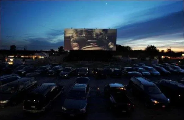 A parking lot with cars parked in front of a large screen