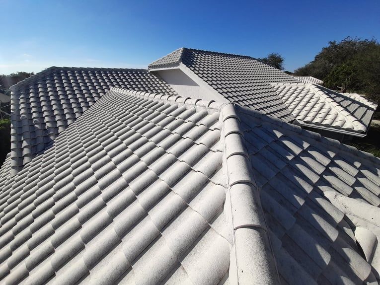 Gray tiled roof of a house under a clear blue sky.