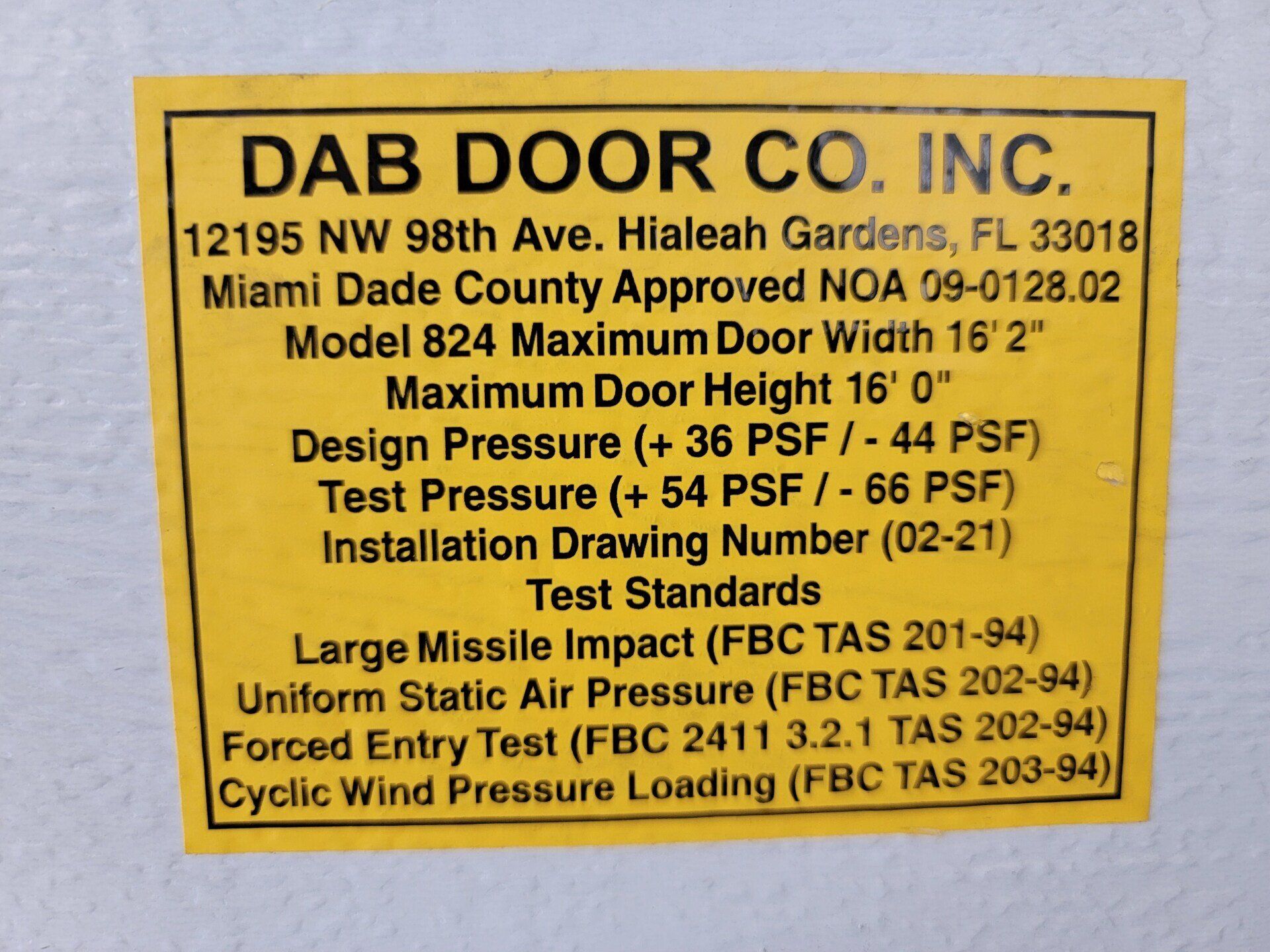 Yellow label: DAB Door Co. Inc. information, Miami-Dade County approved, Model 824, test standards, and installation details.