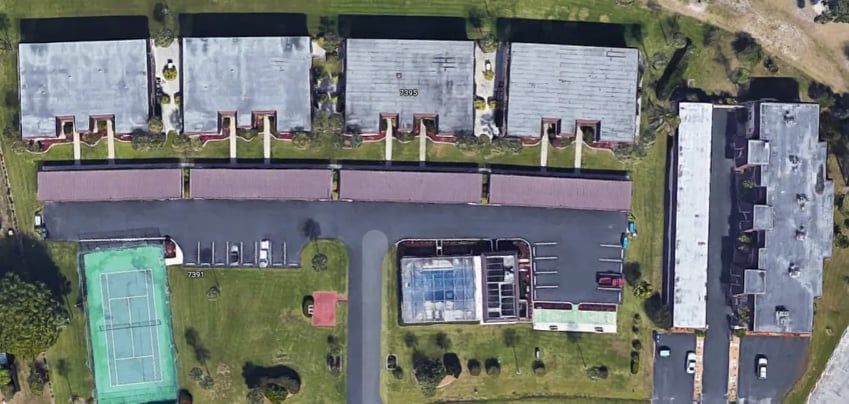 Aerial view of apartment buildings, tennis court, and swimming pool.