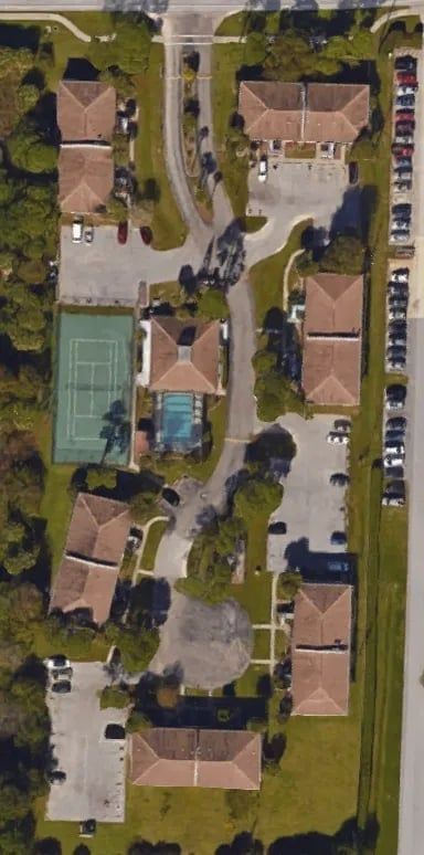 Aerial view of a residential complex with buildings, a tennis court, and a swimming pool.