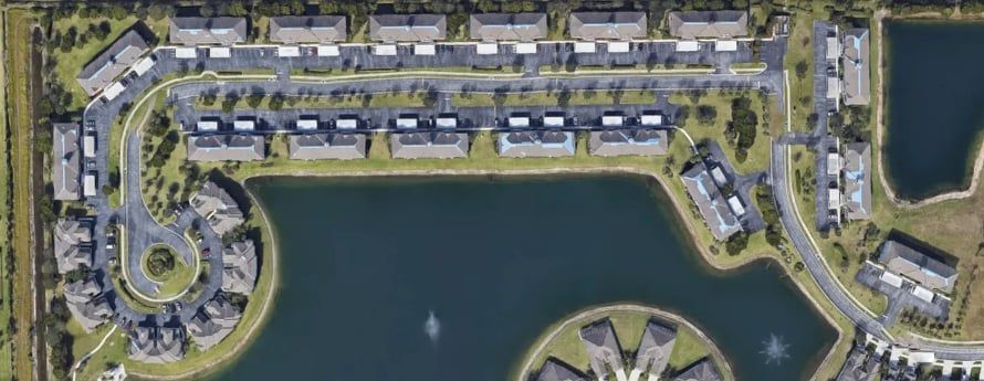 Aerial view of a residential complex with houses, roads, and a lake.