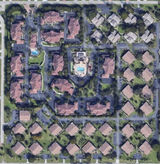 Aerial view of a residential community with buildings, roads, trees, and swimming pools.