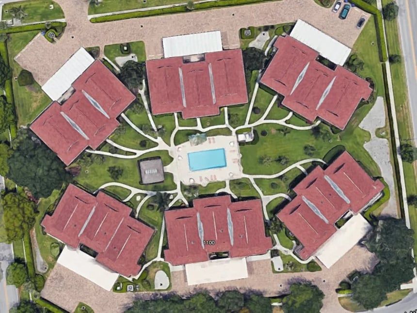 Aerial view of a complex with seven red-roofed buildings arranged around a central courtyard