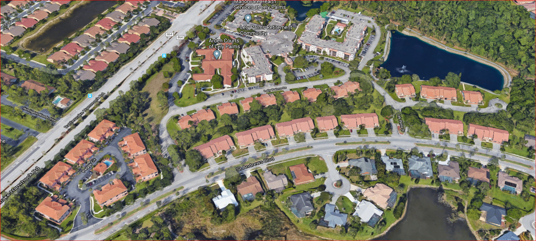 Aerial view of a suburban neighborhood with houses, roads, trees, and water bodies.