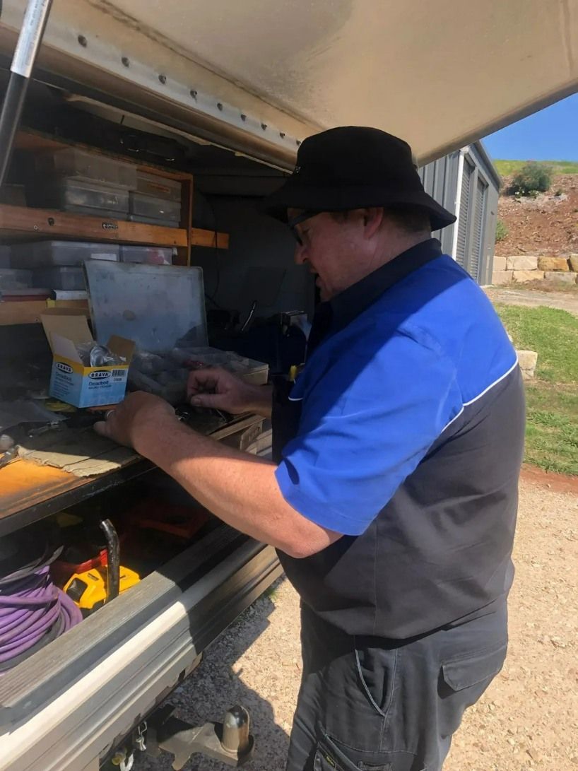 A Man in a Shirt and Black Hat is Working in the Back of a Truck — Suresafe Locksmiths in Glenvale, QLD