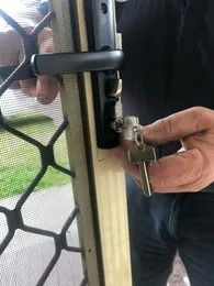 A Man is Holding a Key in Front of a Door — Suresafe Locksmiths in Glenvale, QLD