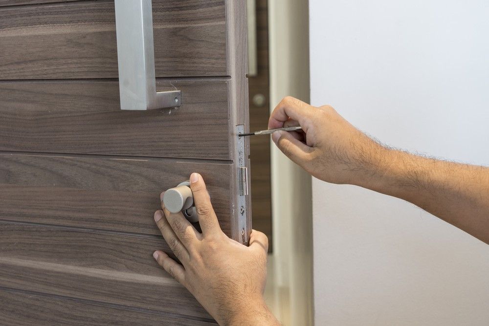 A Person is Fixing a Door With a Screwdriver — Suresafe Locksmiths in Glenvale, QLD