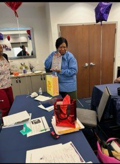 Person opening a gift at a party table with balloons and wrapped presents in the background