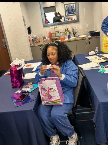 Person in blue outfit opening a gift bag at a decorated table during an indoor celebration