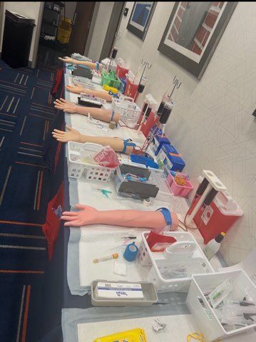 Row of mannequin arms on a long table, likely a beauty or training display, with colorful supplies and tools.