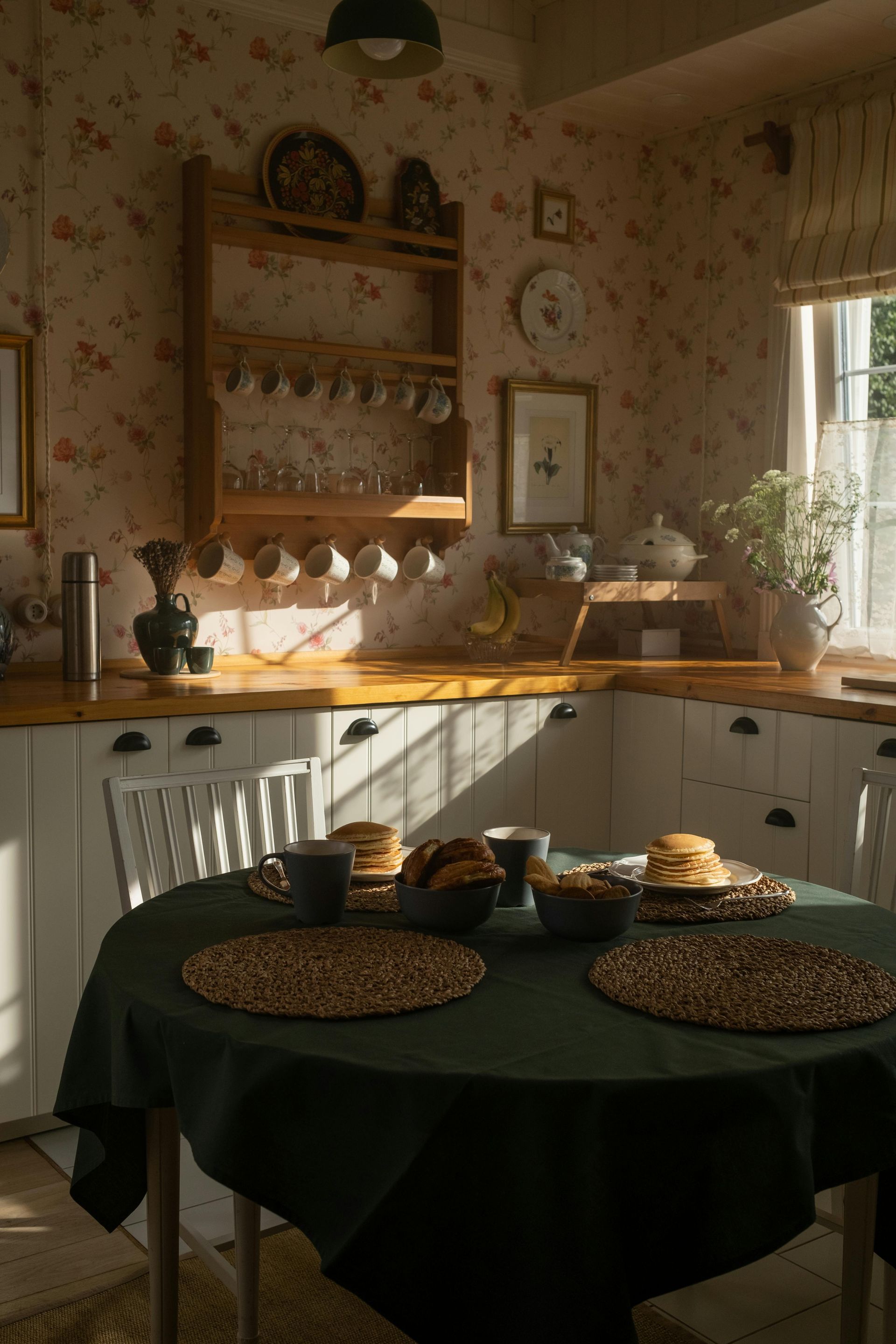 Sunlit rustic kitchen with a round table set for breakfast and shelves of dishes and decor