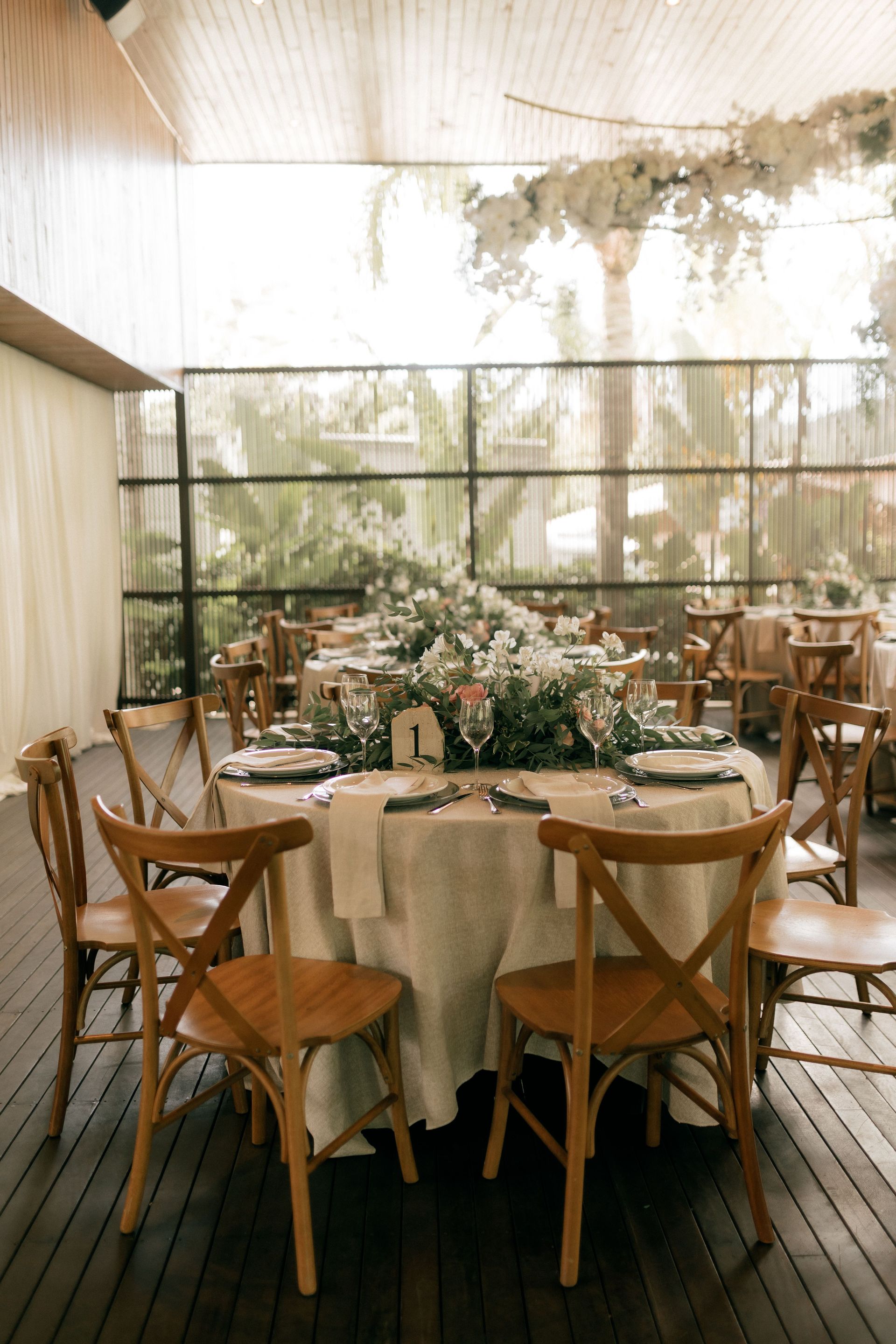 Elegant outdoor dining table with flowers and wooden chairs under a light canopy