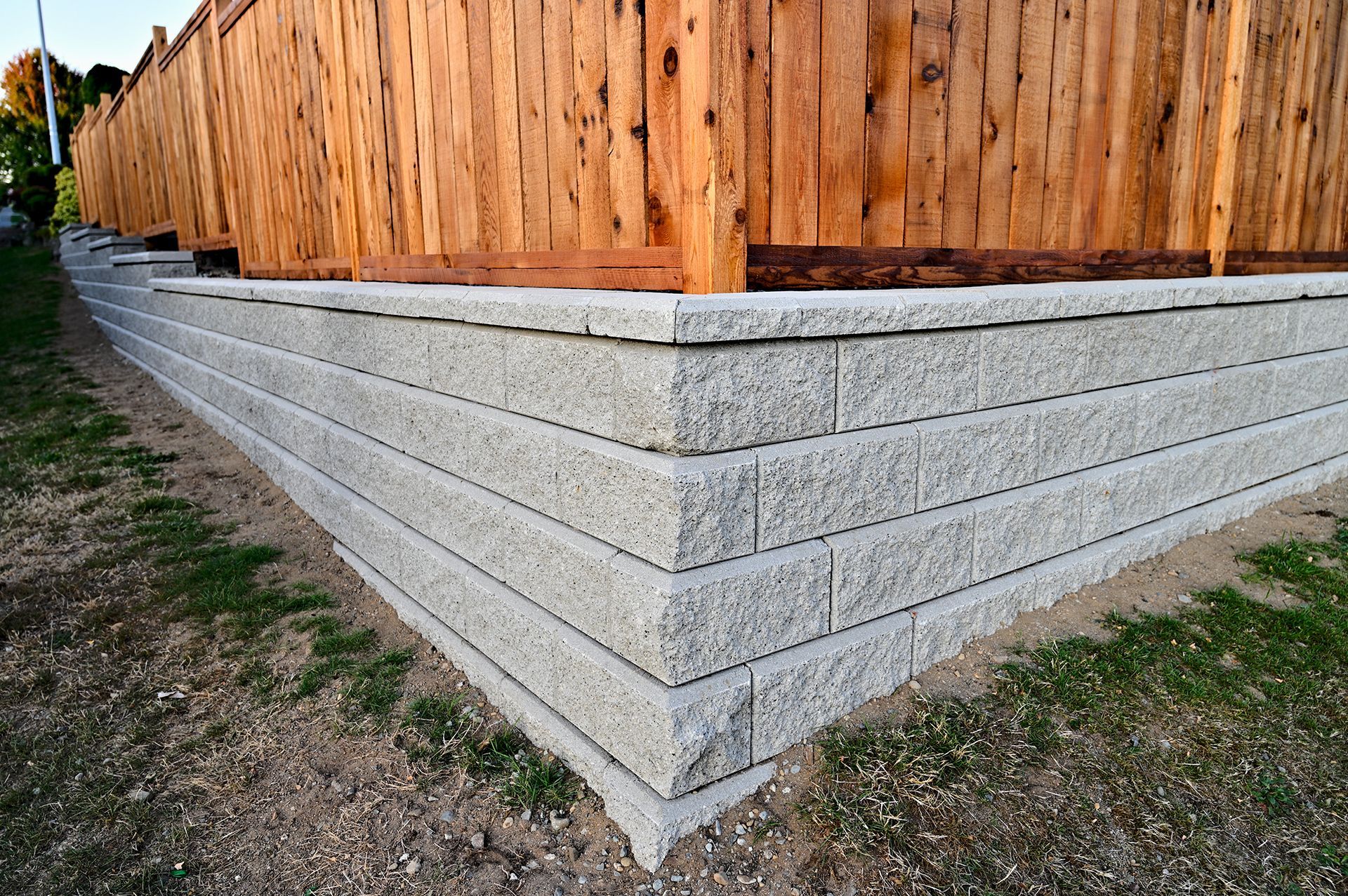 A concrete retaining wall next to a wooden fence.