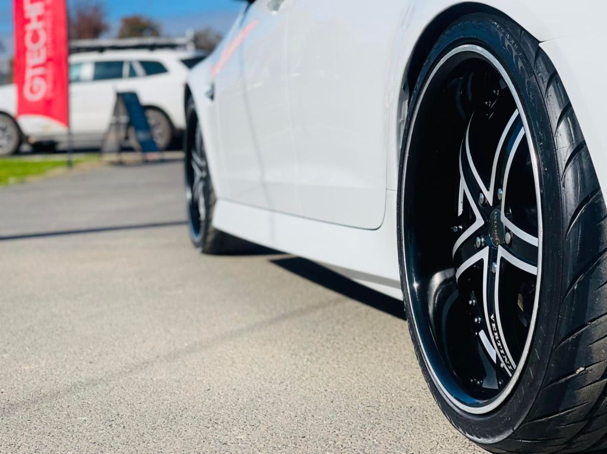 Close-up of a White Sports Car’s Black Alloy Wheel Parked Outdoors on Pavement — Jake's Car Detailing in Taminda, NSW