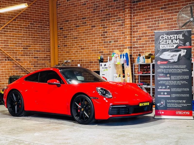 Red Sports Car Displayed Indoors Beside a Crystal Ceramic Shield Sign — Jake's Car Detailing in Taminda, NSW