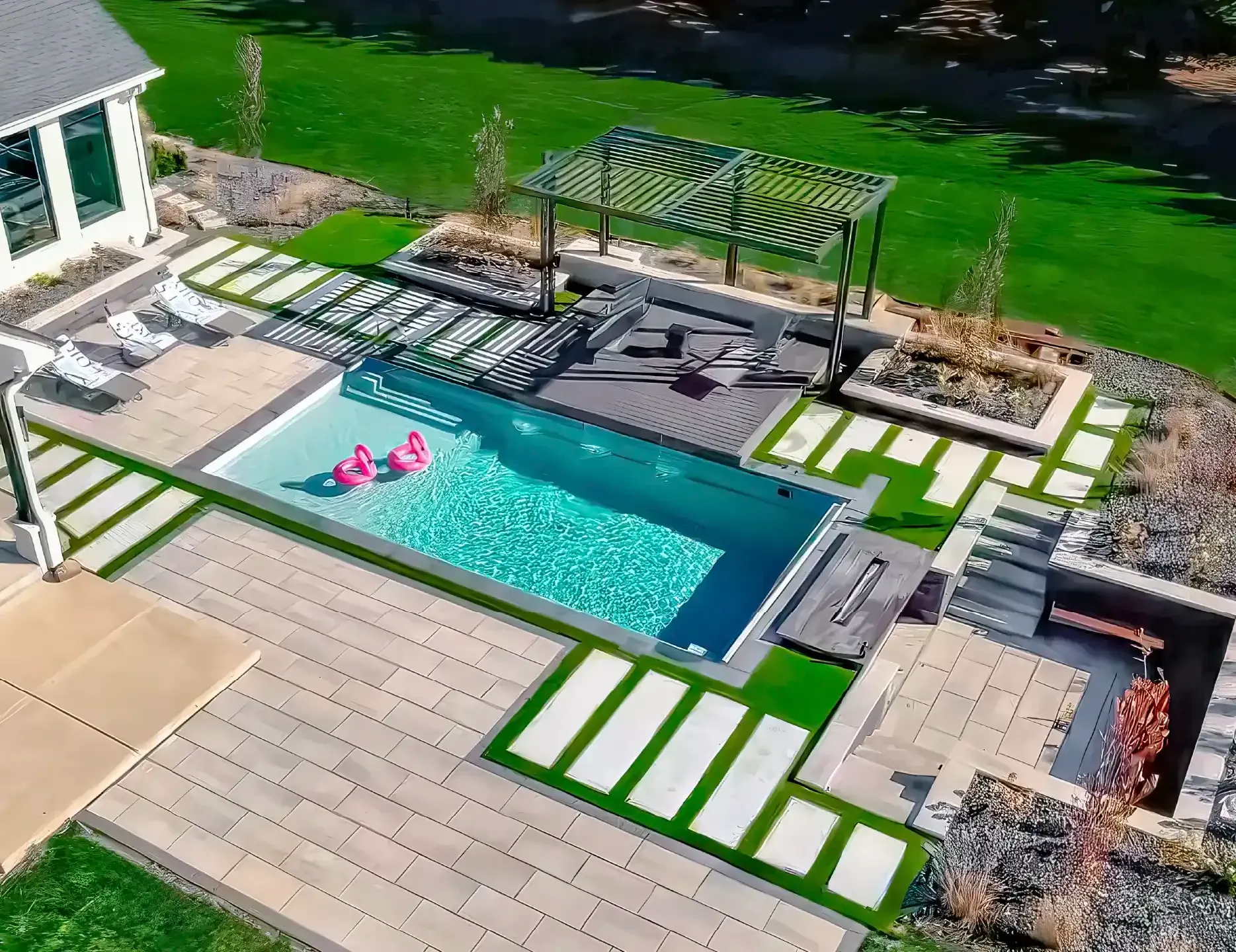 Backyard patio with a narrow turquoise pool, white loungers, pergola, and green lawn borders