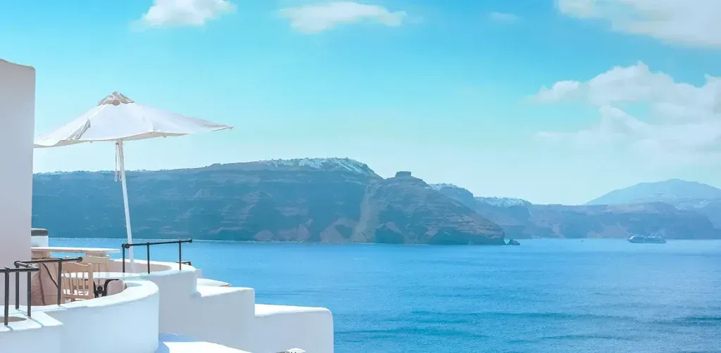 White terrace overlooking a calm blue sea and distant green islands under a clear sky