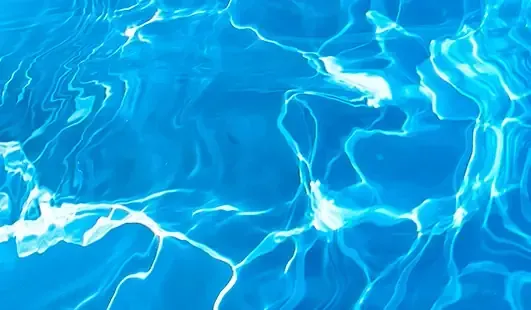 Blue swimming pool water with bright sunlit ripples