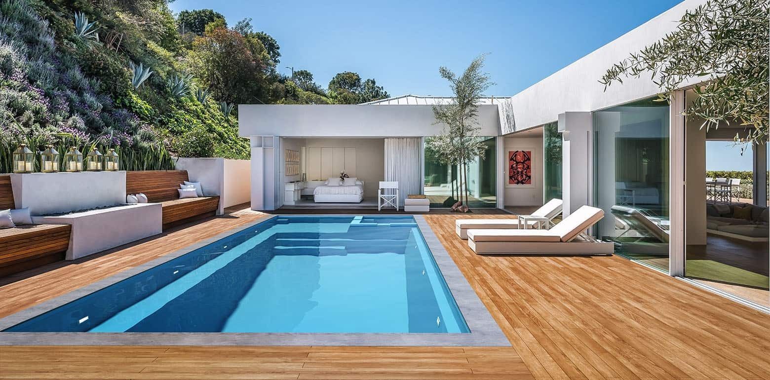Modern backyard with turquoise pool, wooden deck, white lounge seating, and a sleek patio pavilion