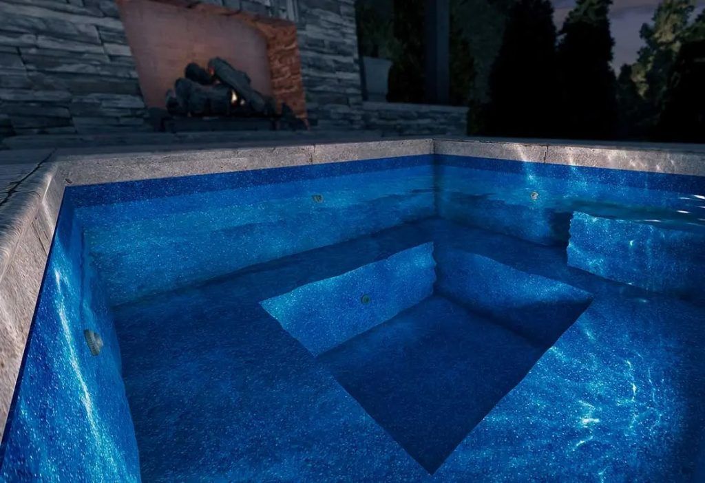 Blue-lit swimming pool with geometric steps and a dark evening patio backdrop