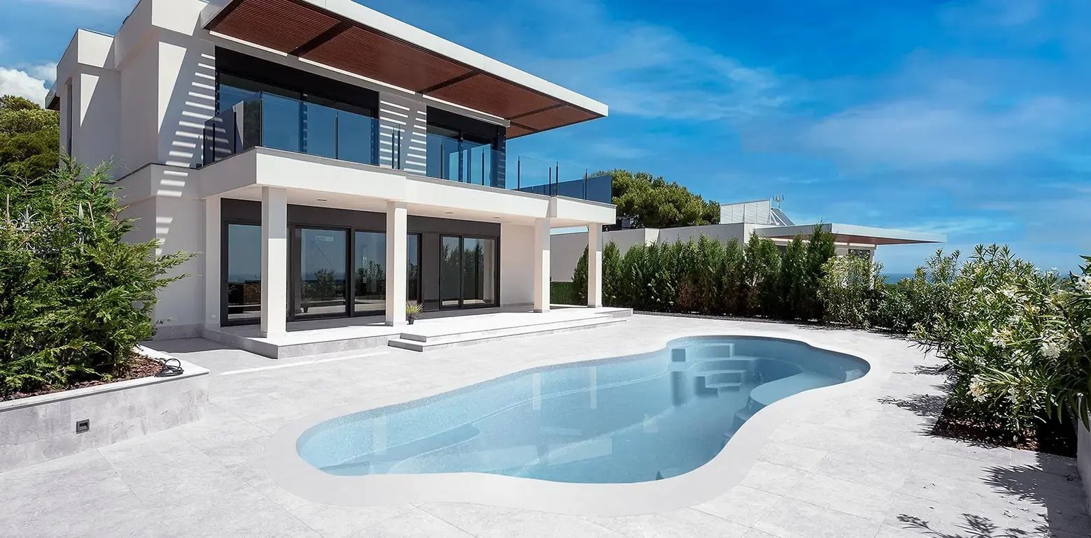 Modern white two-story house with a pool and patio under a blue sky