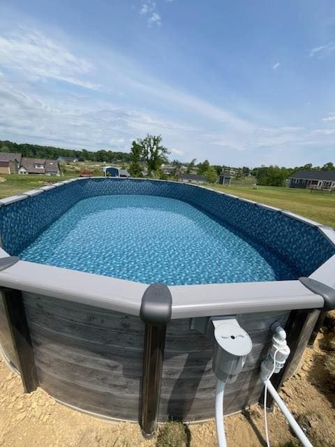 Above-ground pool with blue liner and gray top rail in a backyard under a clear sky