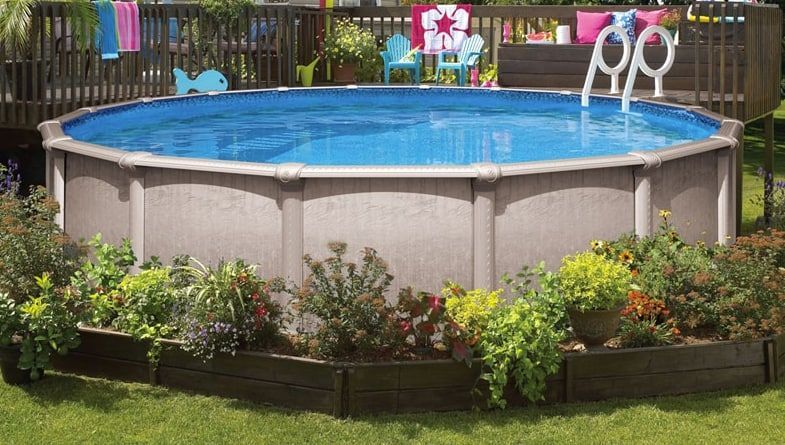 Above-ground backyard pool with blue water, surrounded by flowers and a grassy lawn