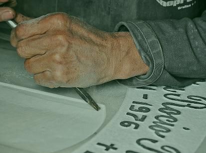 Hand holding a pencil over paper with handwritten notes on a desk