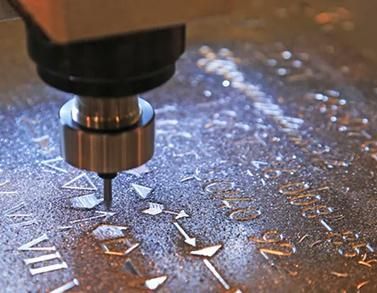 CNC router engraving metallic letters on a reflective surface