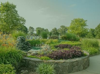 Curved stone planter with colorful flowers and lush greenery in a landscaped garden path