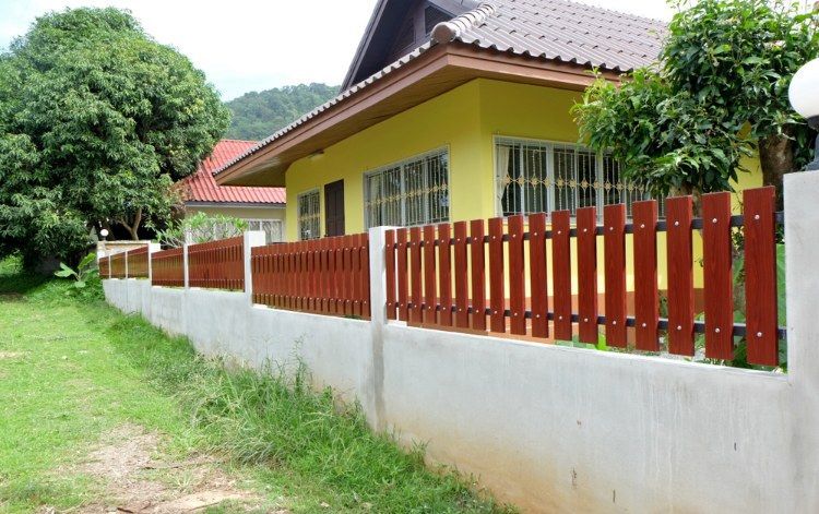 Yellow House With a Red Fence in Front of It — Lange’s Fencing & Landscaping Centre in Island Plantation, QLD