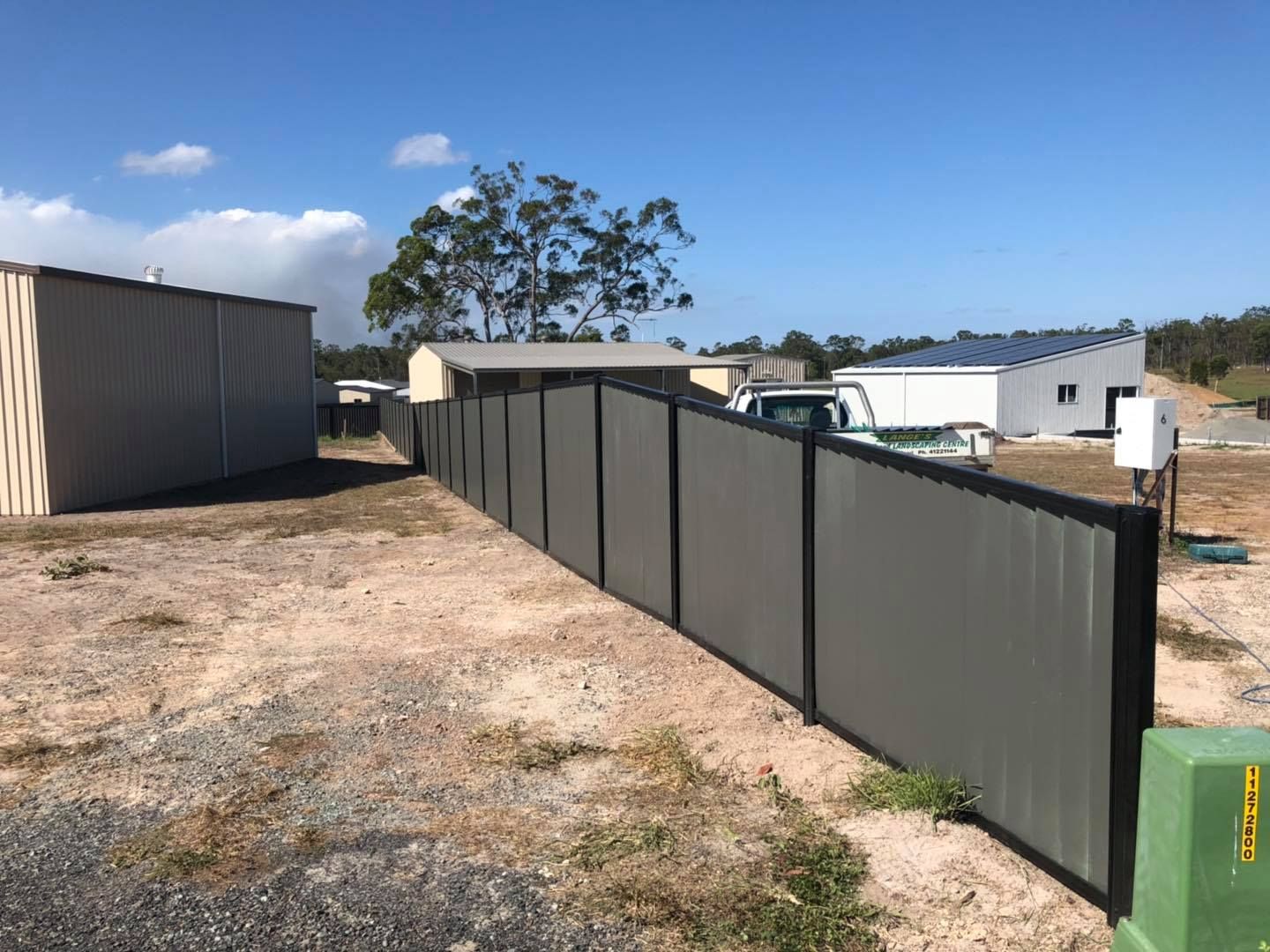 Long Fence Surrounds a Dirt Field With a Shed in the Background — Lange's Fencing & Landscaping Centre in Island Plantation, QLD