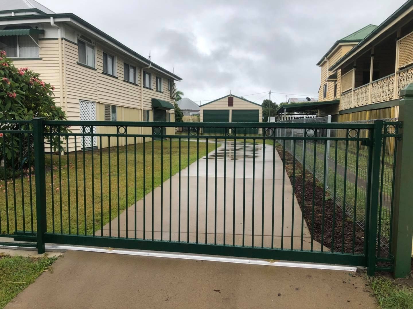 Green Metal Gate Opens to a Concrete Driveway — Lange's Fencing & Landscaping Centre in Island Plantation, QLD