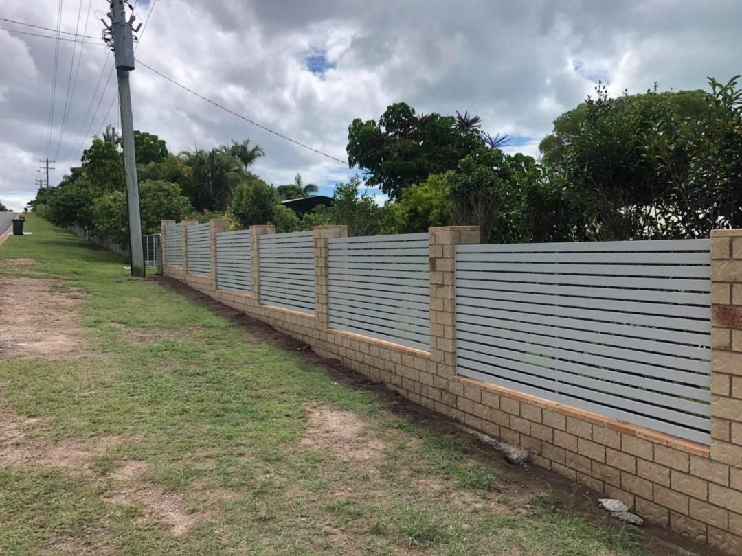 Fence Made of Bricks and Aluminum is Surrounding a Grassy Field — Lange's Fencing & Landscaping Centre in Maryborough, QLD