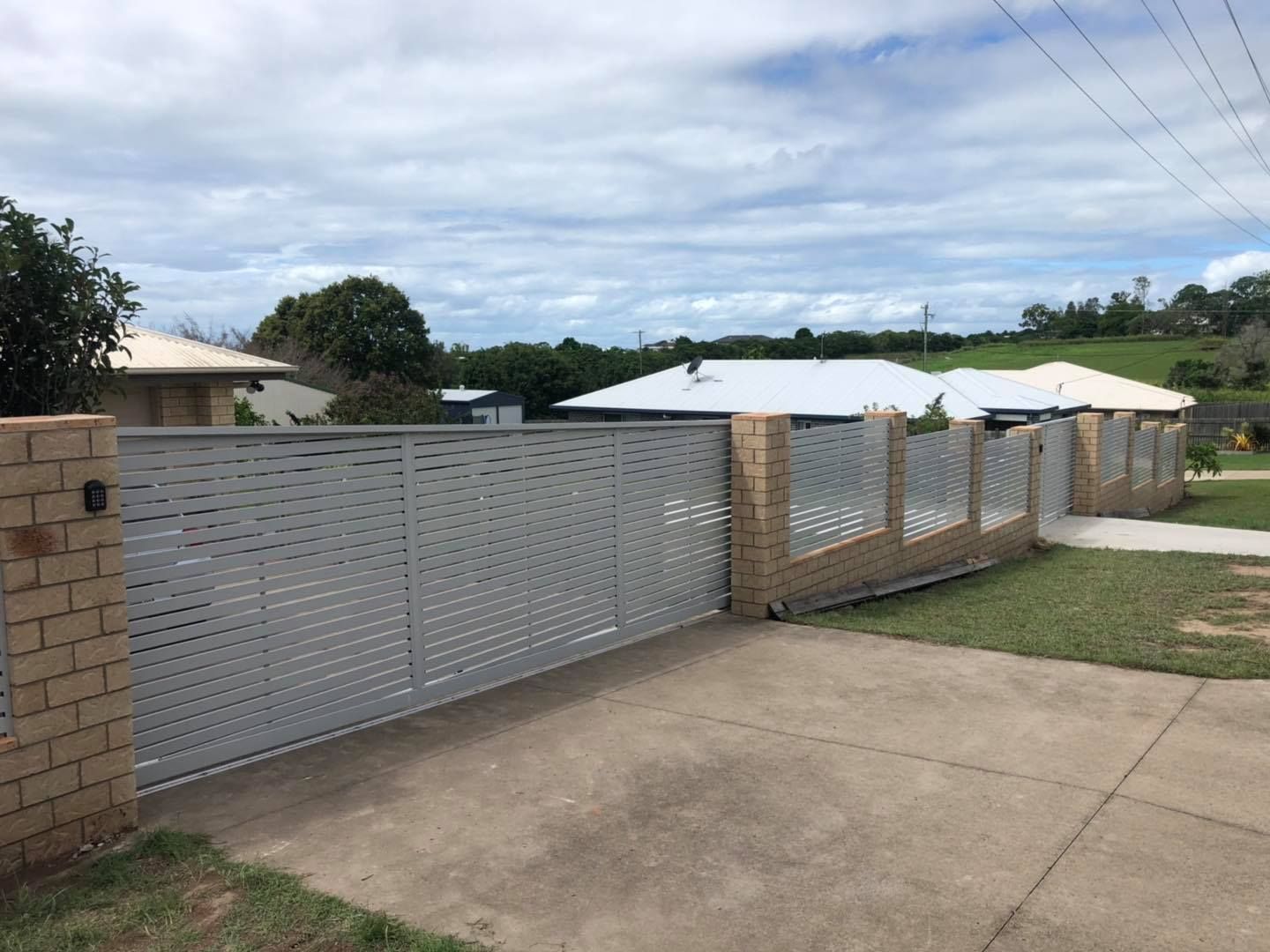 White Fence Surrounds a Driveway in Front of a House — Lange’s Fencing & Landscaping Centre in Island Plantation, QLD