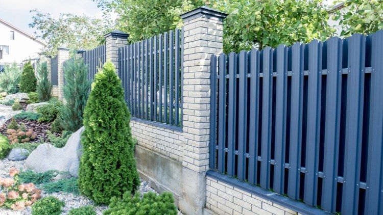 Blue Picket Fence Surrounds a Brick Wall in a Garden — Lange's Fencing & Landscaping Centre in Island Plantation, QLD