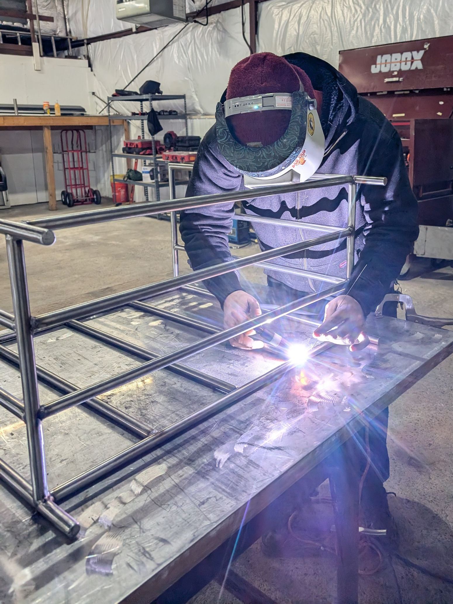 A man is welding a piece of metal in a workshop.