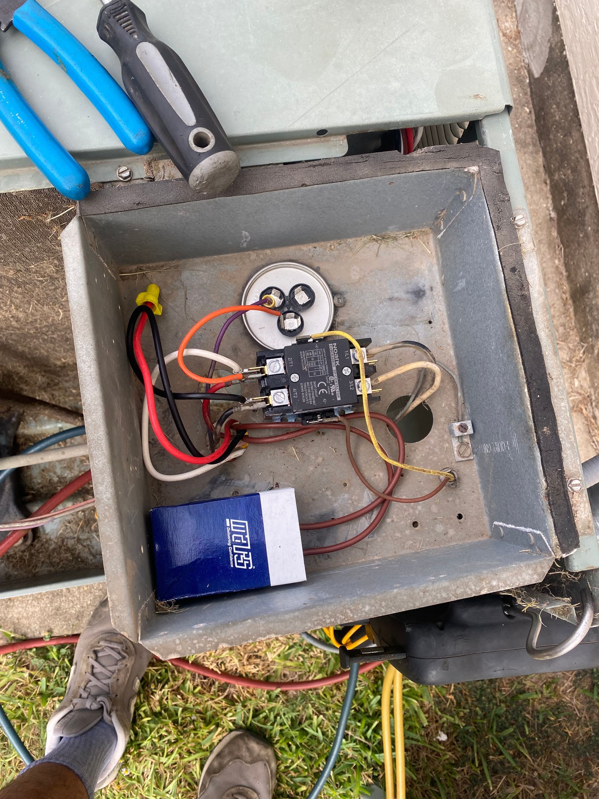 A person is standing next to a box with wires in it.