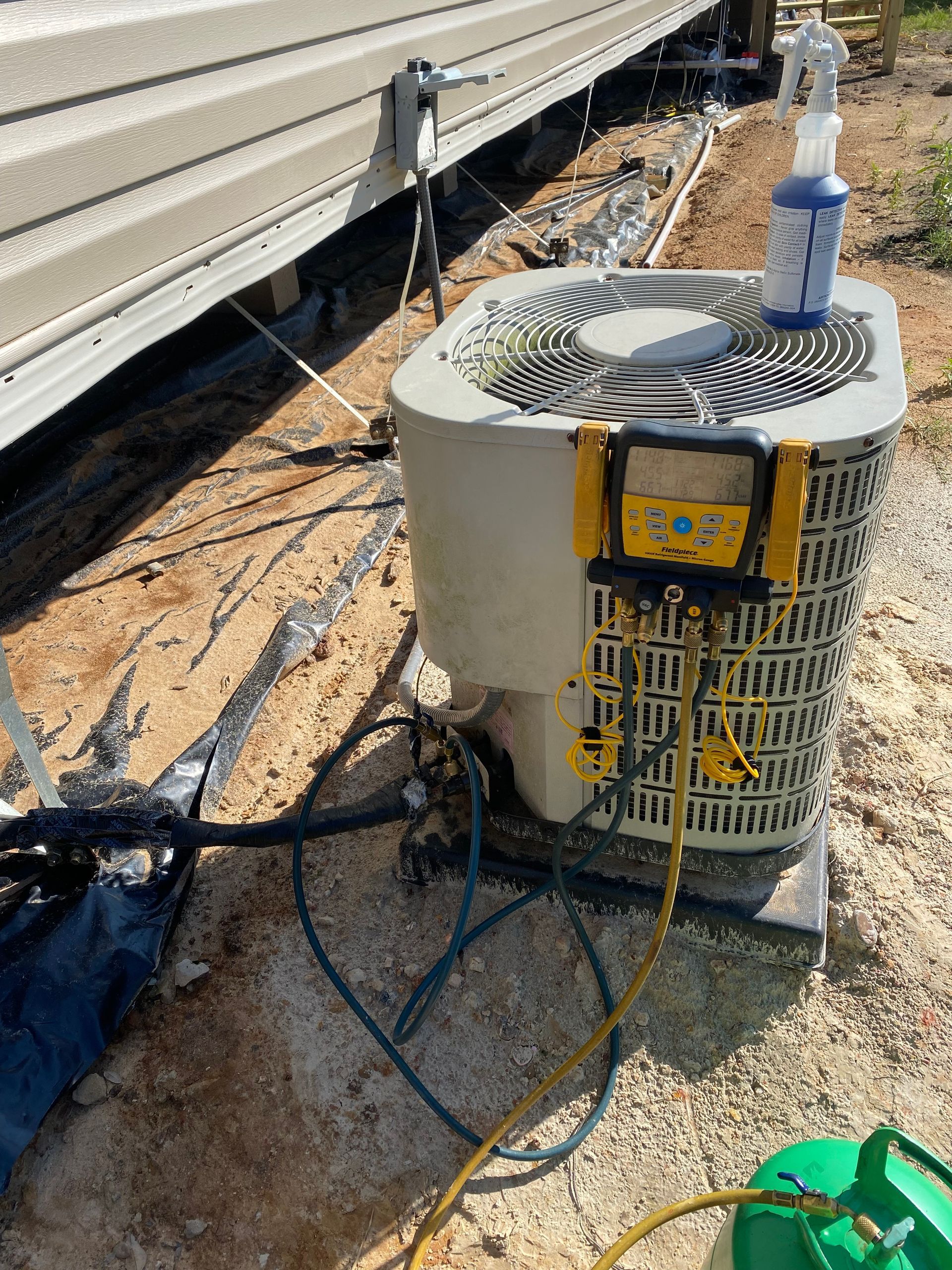 An air conditioner is being serviced outside of a building.