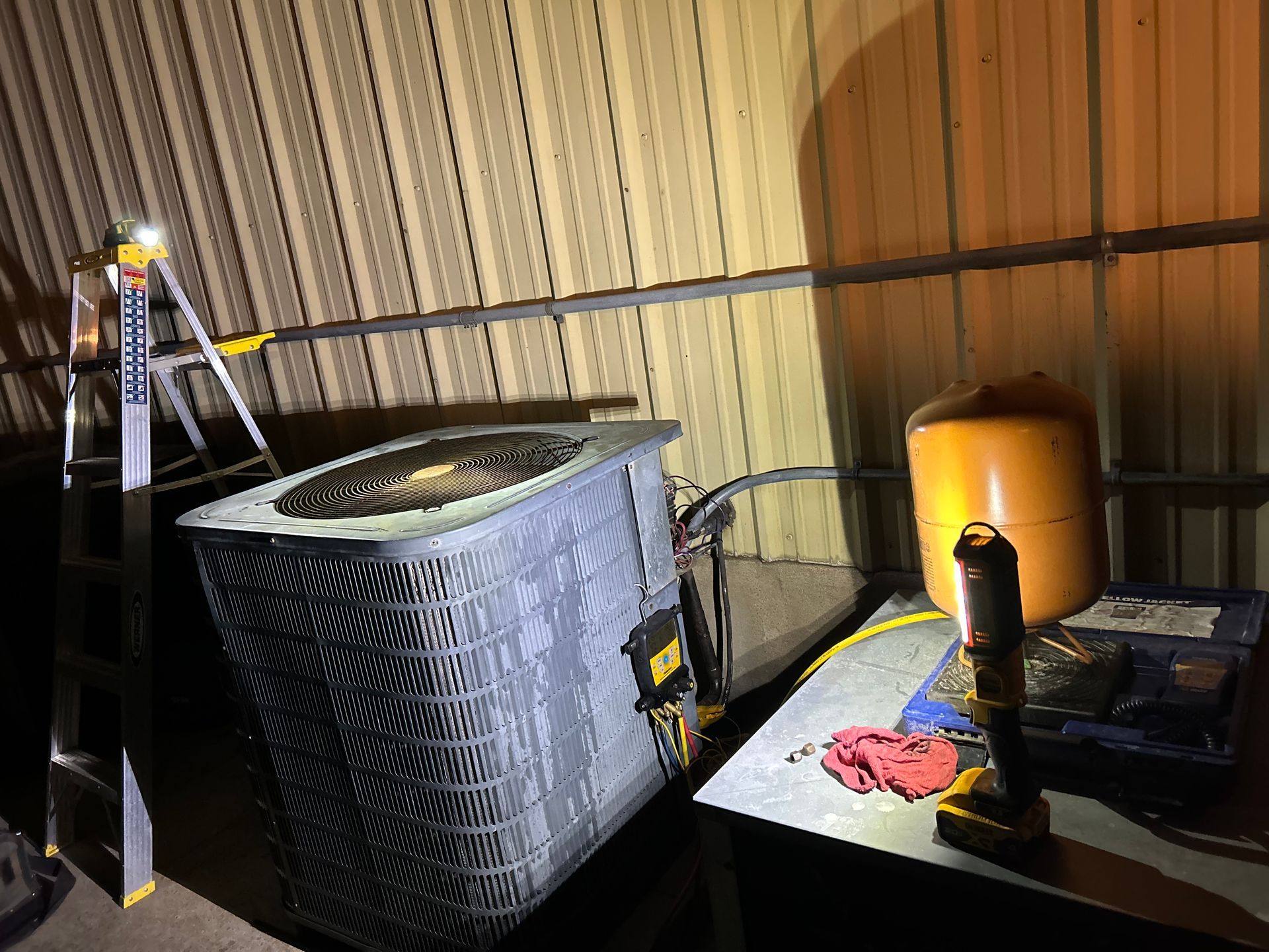 An air conditioner is sitting on top of a table next to a ladder.