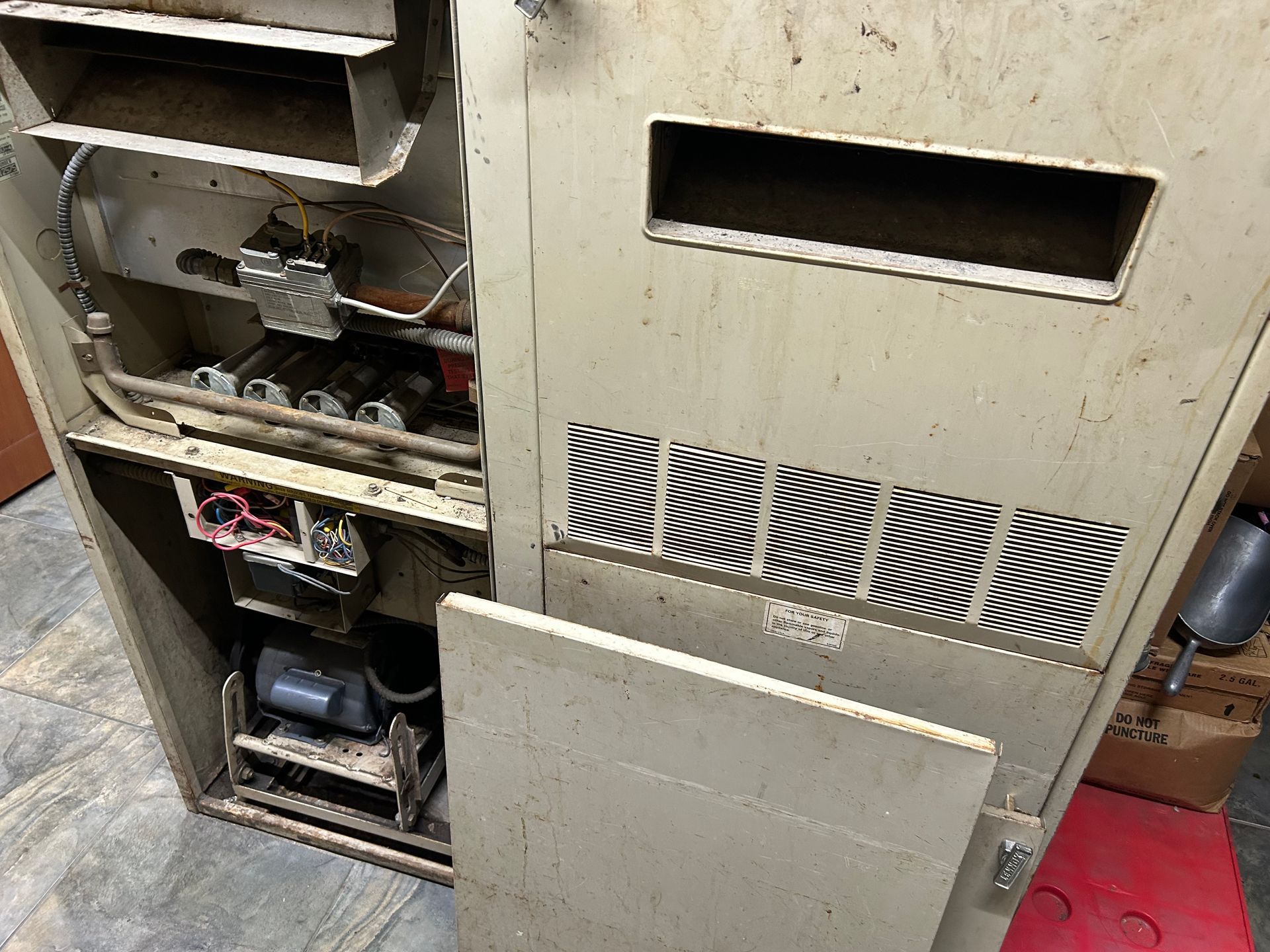 A dirty electrical box with the door open and a lot of wires coming out of it.