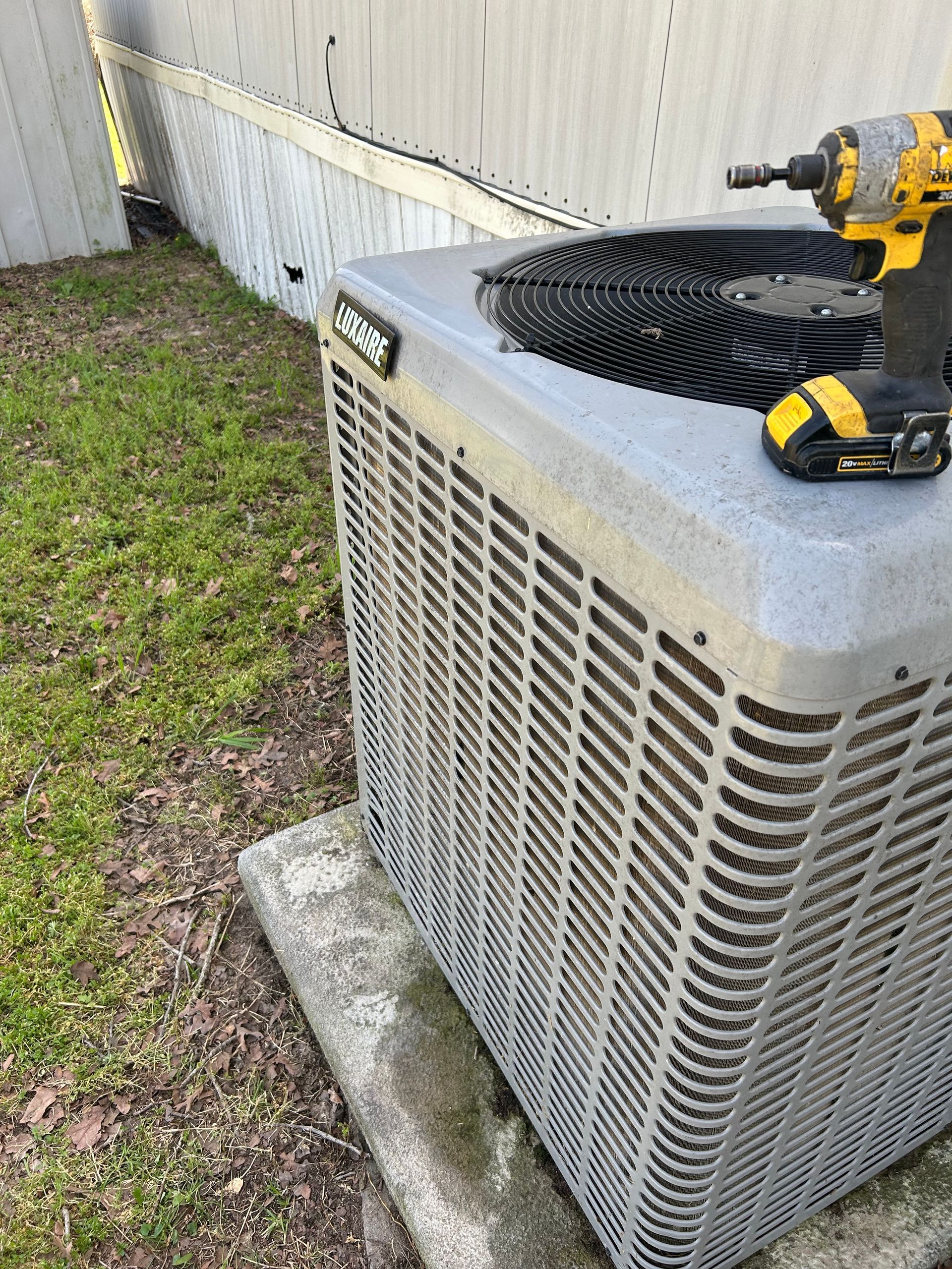 A drill is sitting on top of an air conditioner.