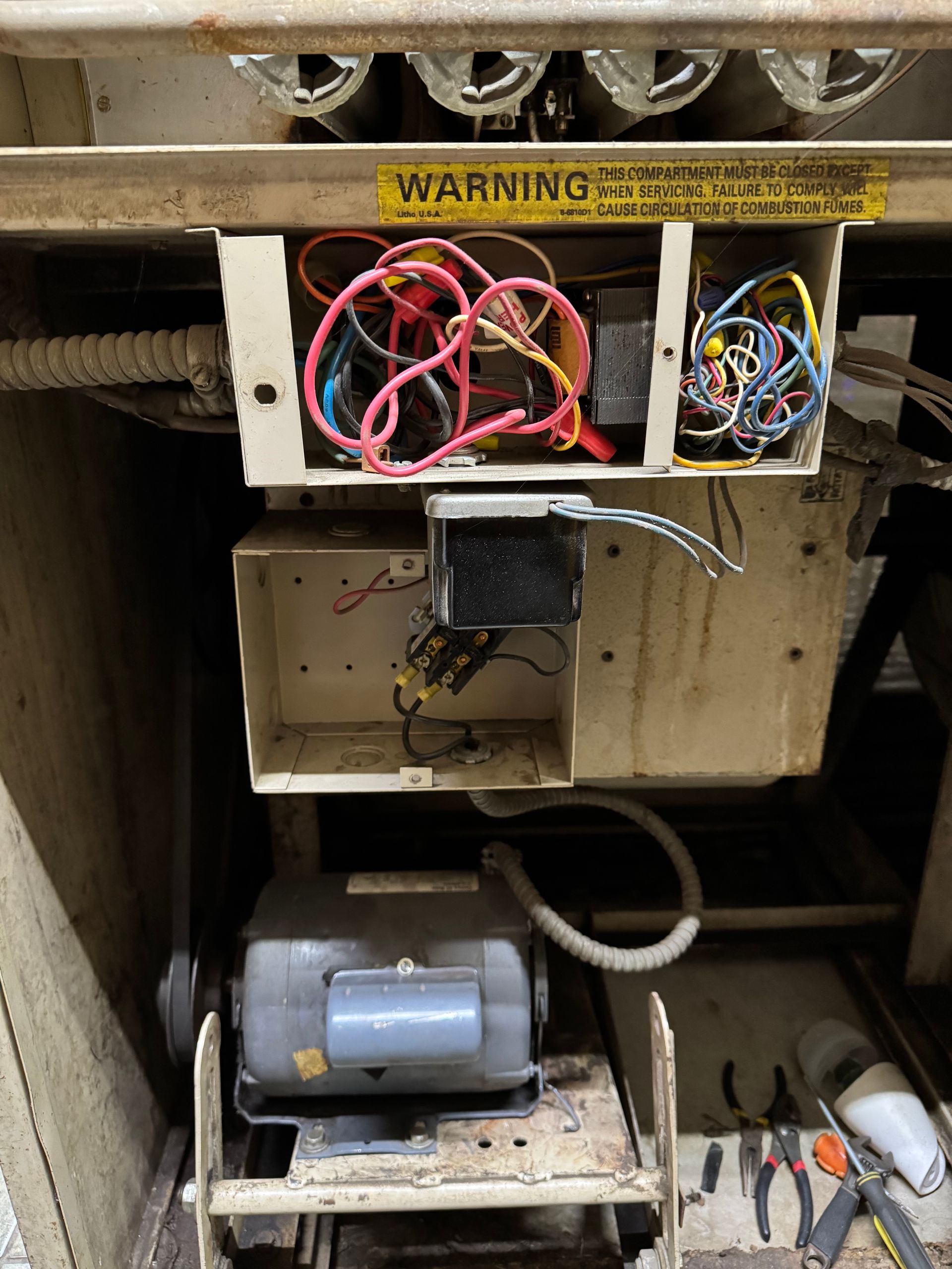 A warning sign is on the side of a machine with wires coming out of it.