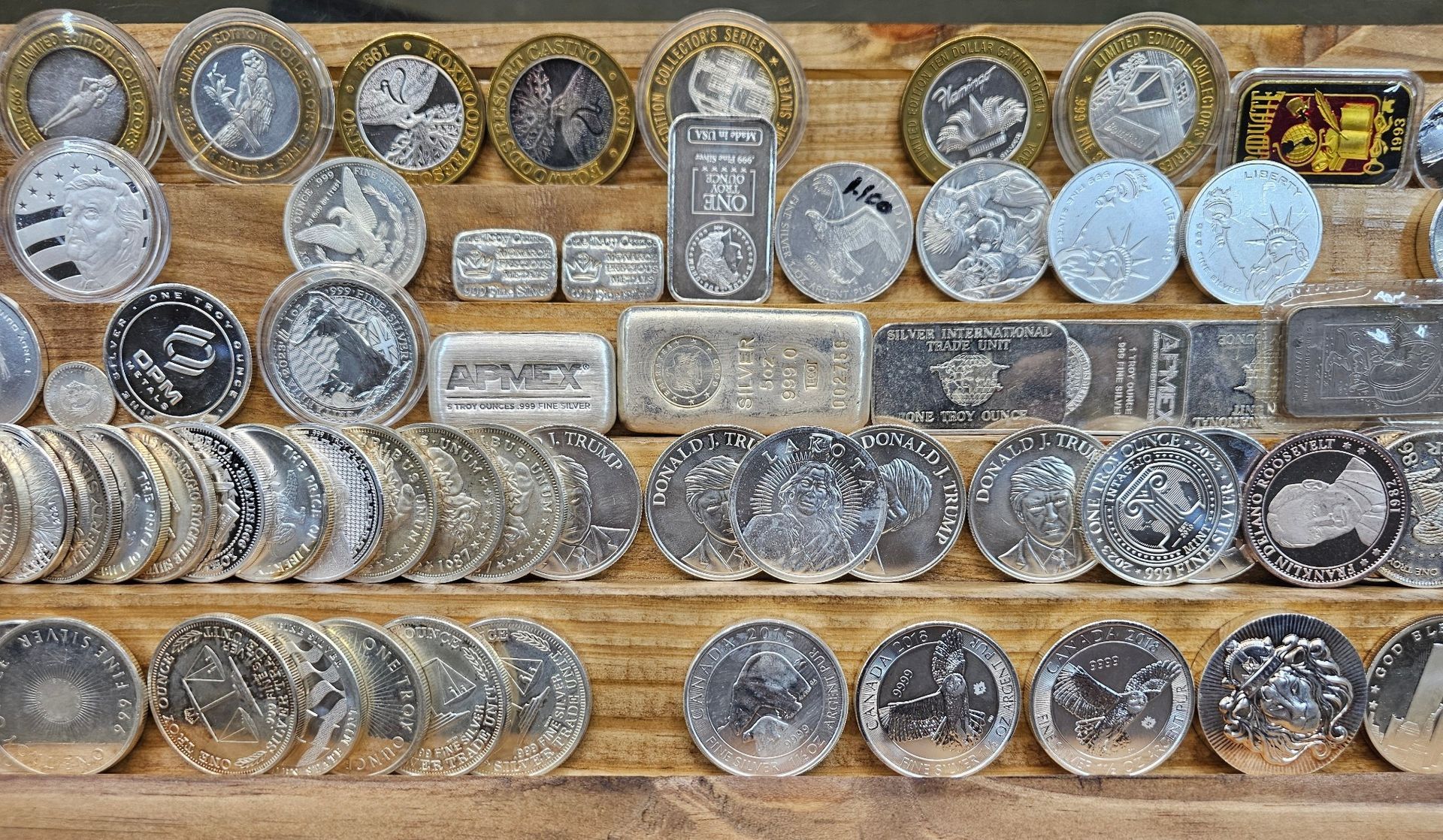 Rows of assorted coins and metal tokens arranged in a display on a textured beige surface