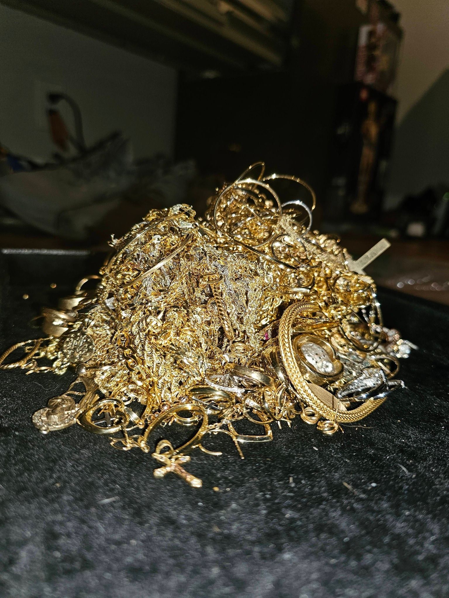 Pile of tangled gold necklaces and jewelry on a dark surface